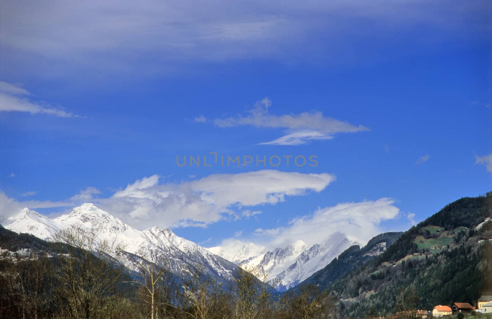 The snowy peaks of the Alps against a bright blue sky.