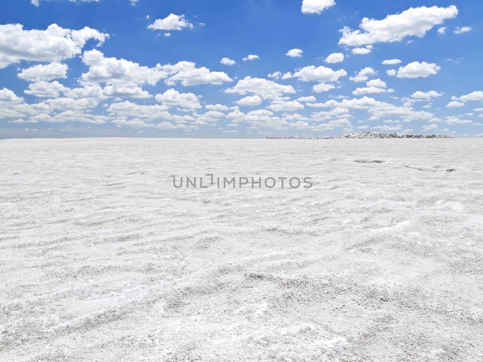 Large open salt mine under a bright blue sky.