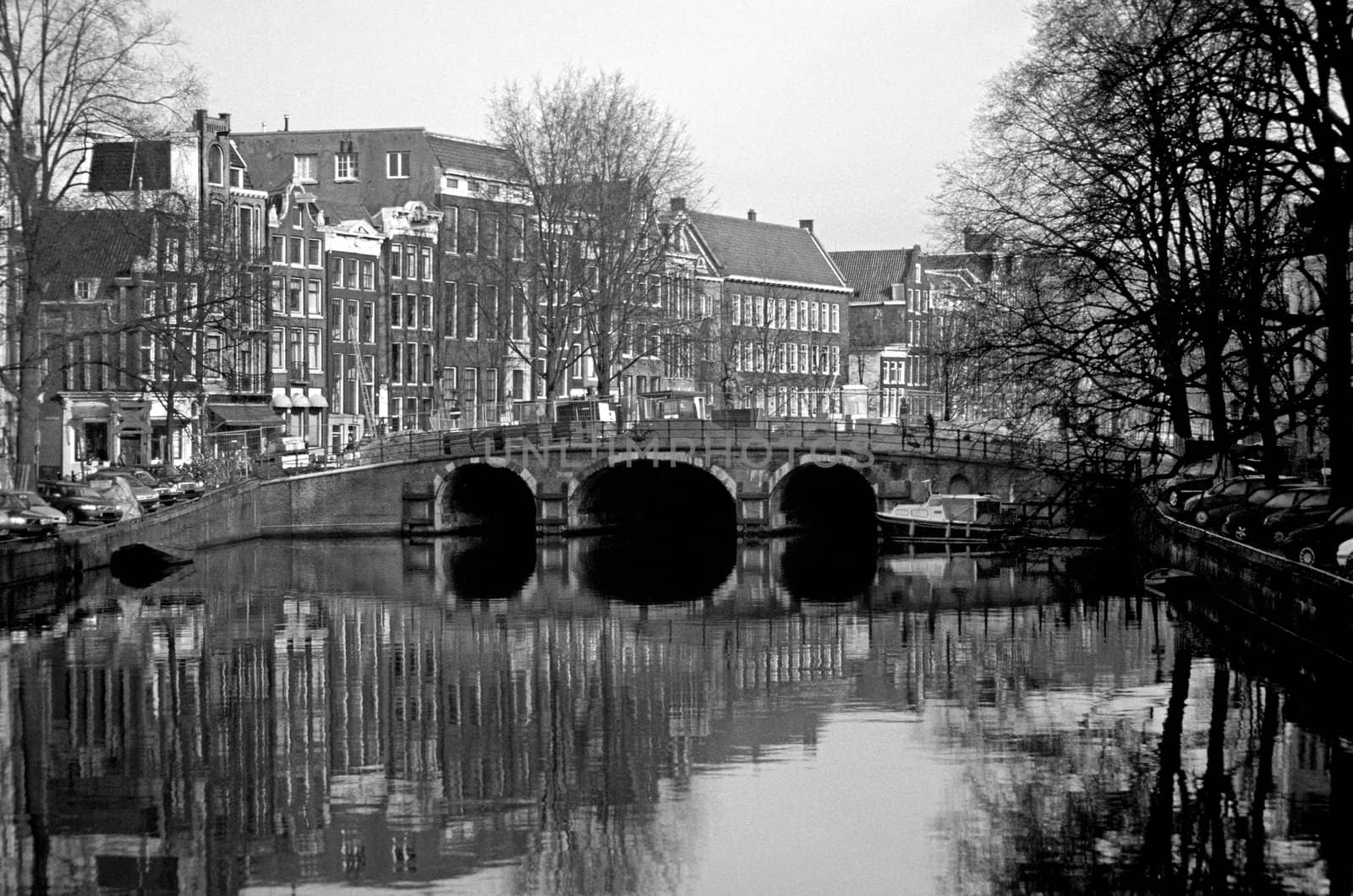 Traditional canal houses line a canal spanned by a scenic bridge in Amsterdam, the Netherlands.