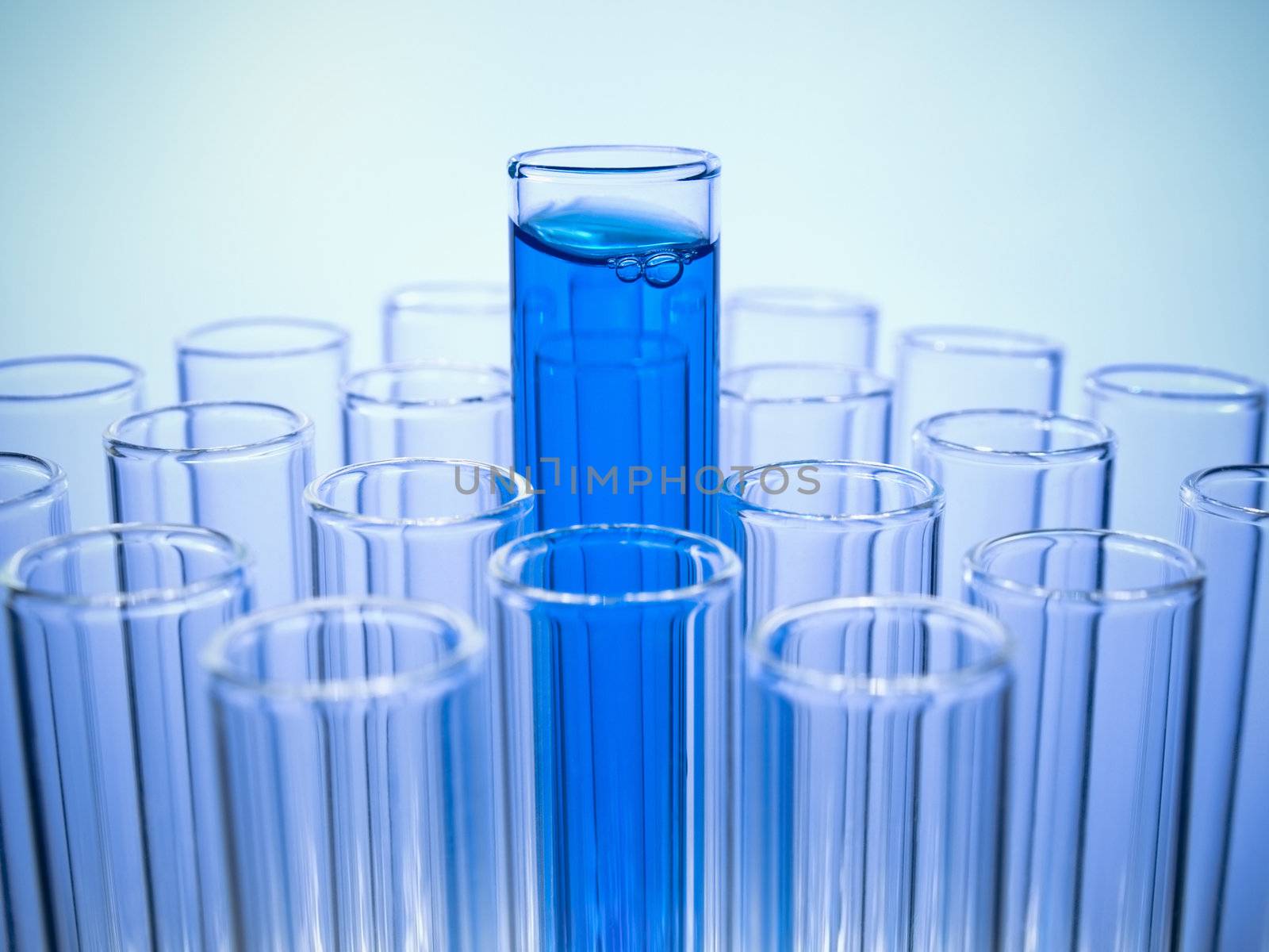 A test tube filled with blue liquid coming out of many empty test tubes.