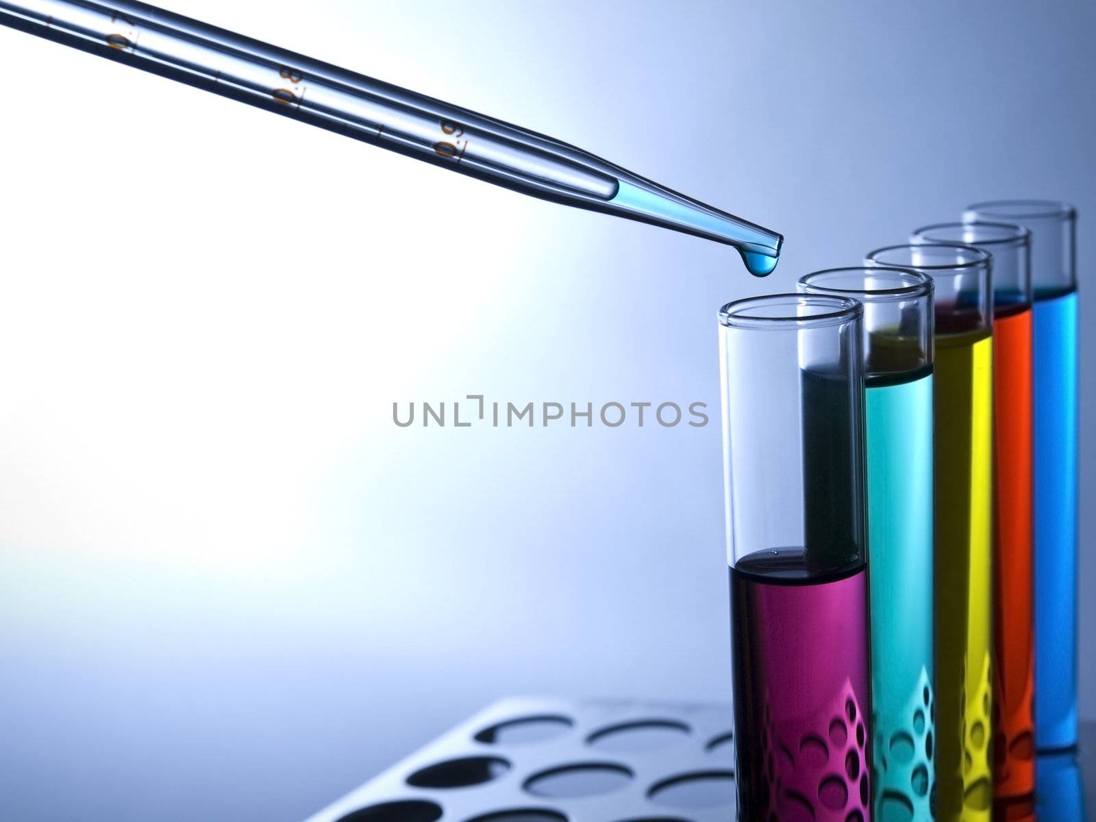 Close up of test tubes filled with color liquids and a pipette.