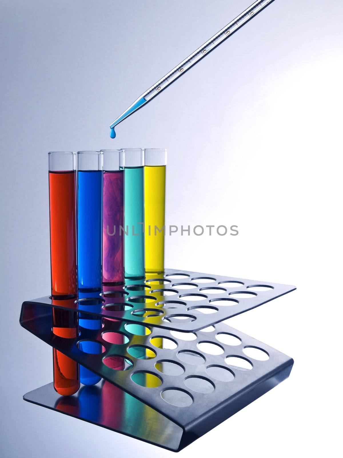 Close up of test tubes filled with color liquids and a pipette.