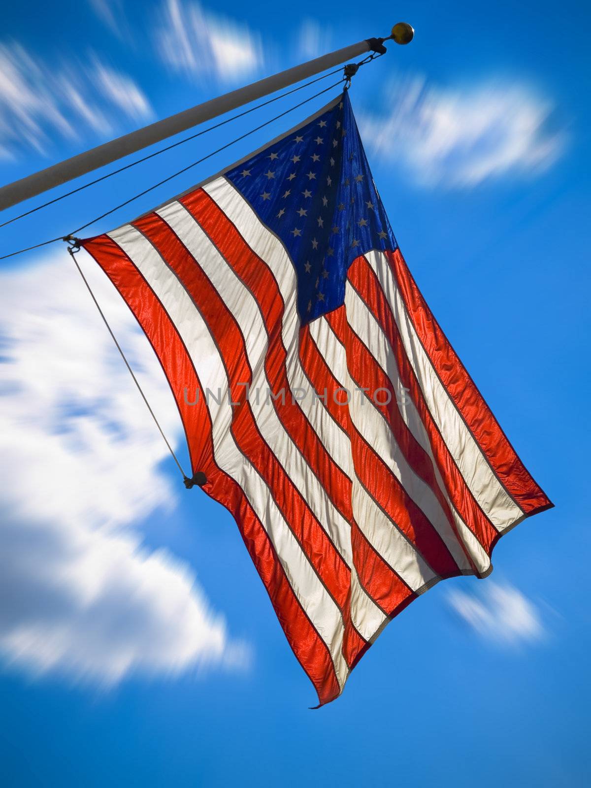 An american flag waving over a blue sky. Zooming effect.