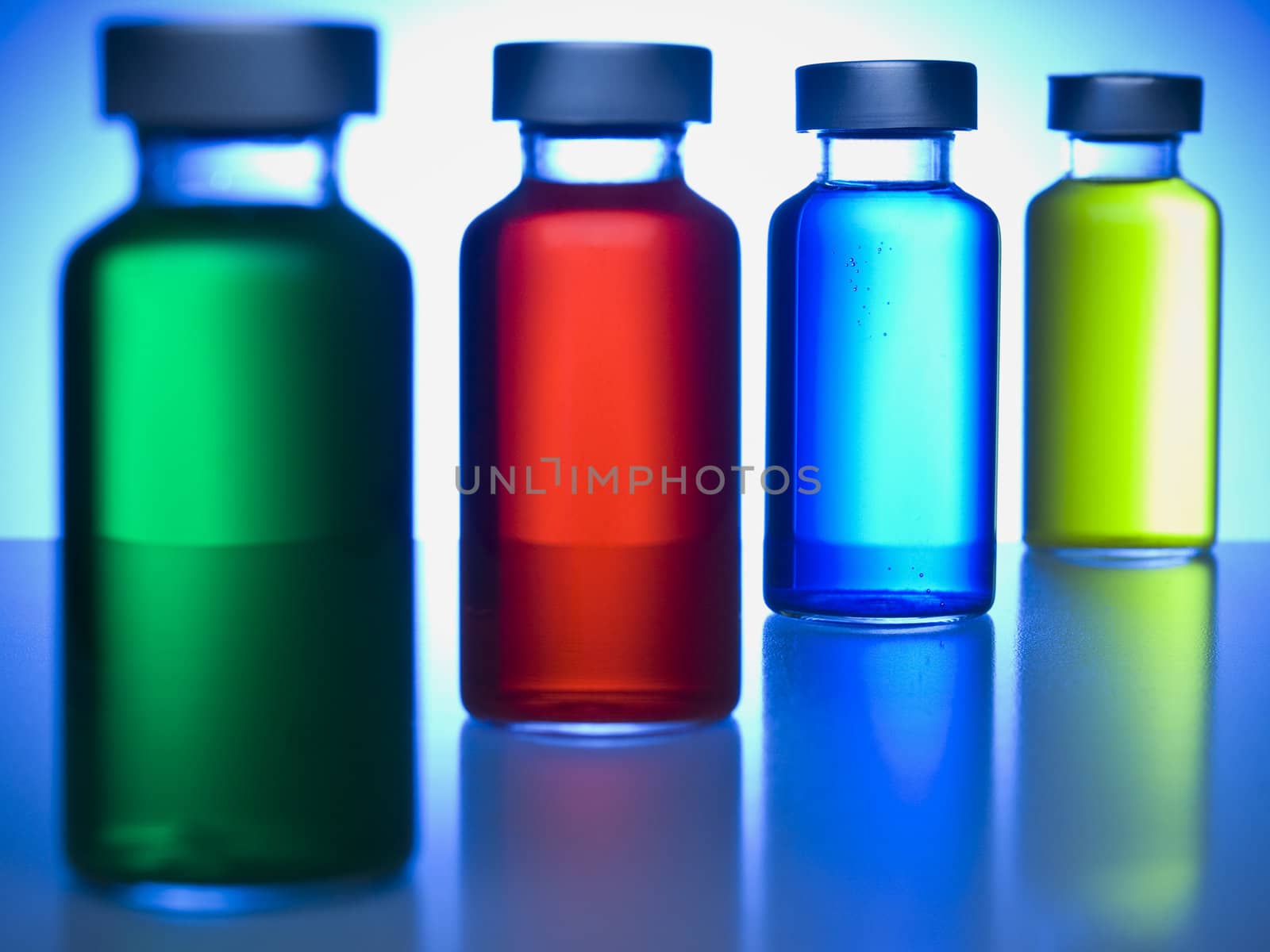 A row of vials filled with colored liquids. Focus on the blue one.