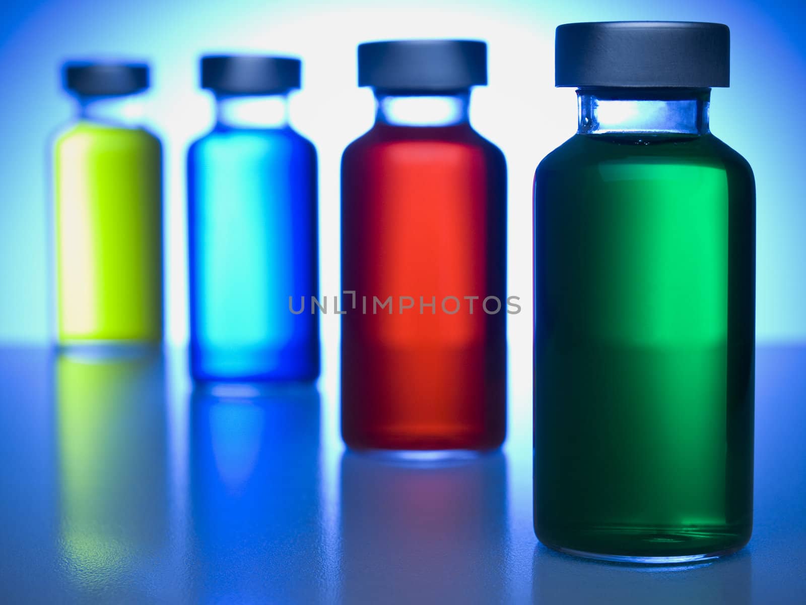 A row of vials filled with colored liquids. Focus on the green one.
