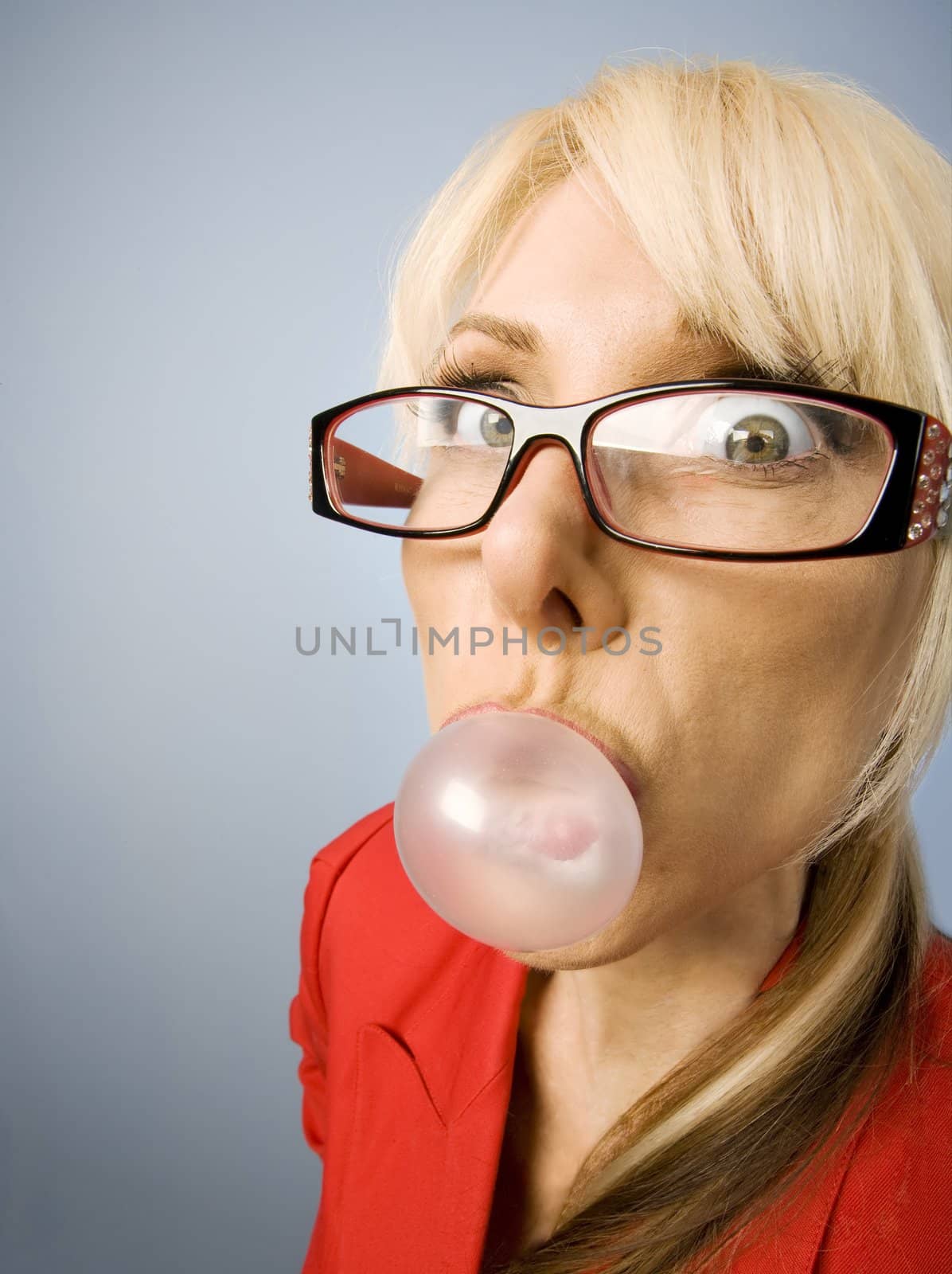 Woman in red with glasses blowing a bubble 