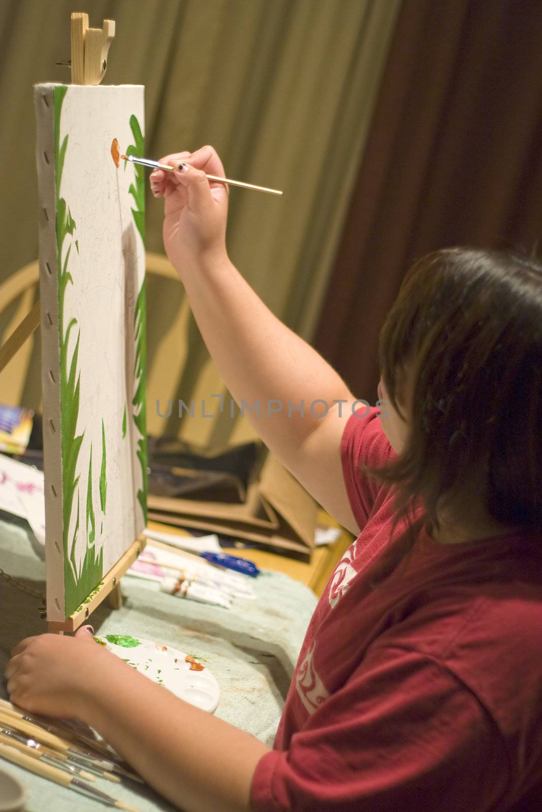 A young woman doing working with oil paints on canvas.