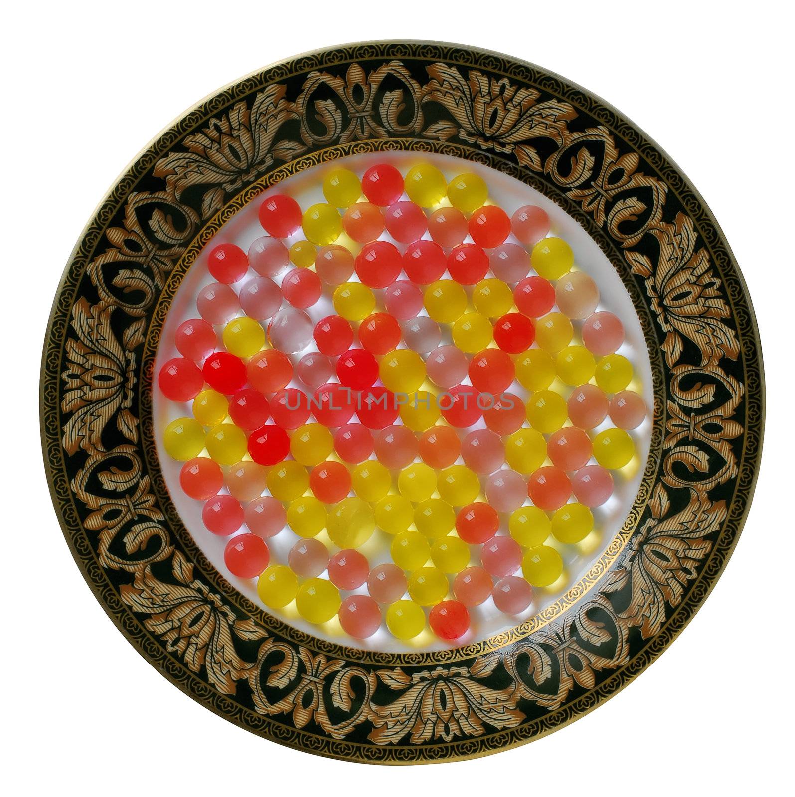 Color wet sweet gelatine balls on decorative plate. Isolated on white.