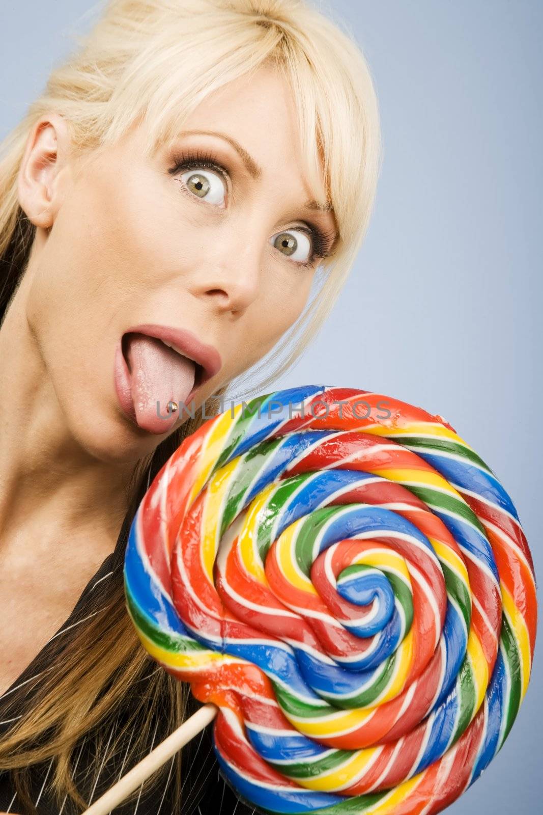 Woman with a pierced tongue licking a big colorful lollipop