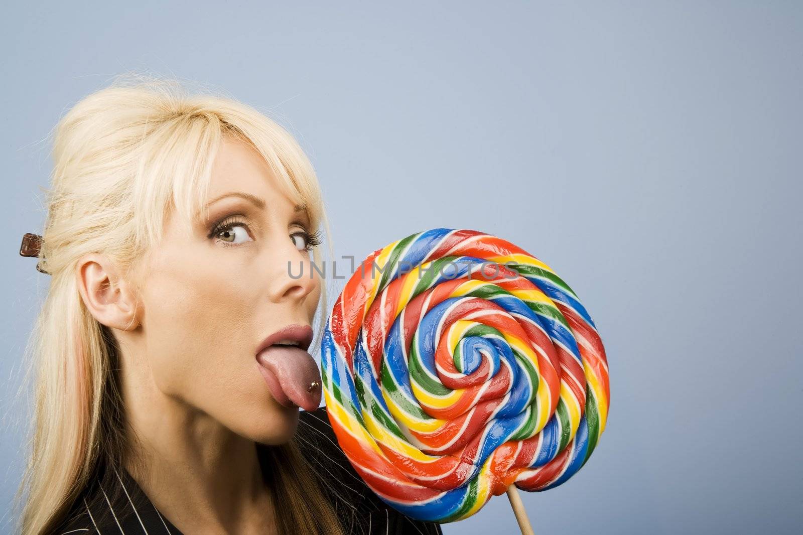 Woman with a pierced tongue licking a big colorful lollipop