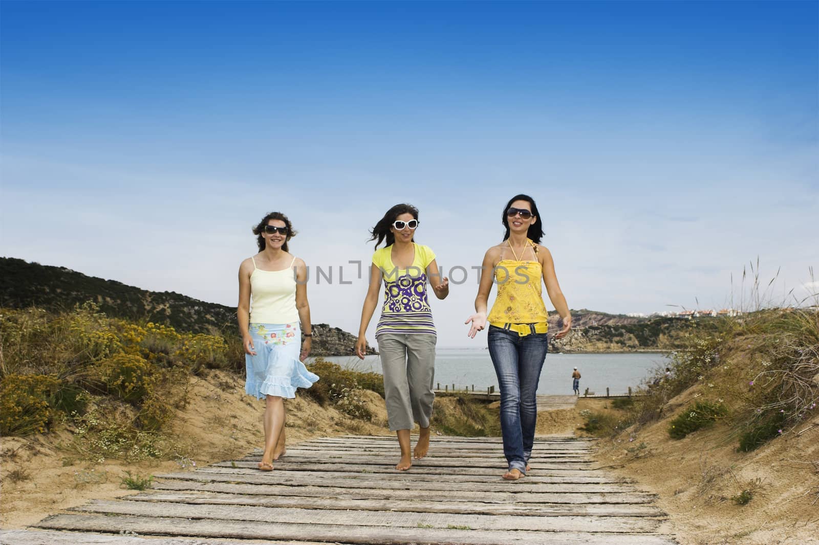 Three young girls walking with a beach on the background