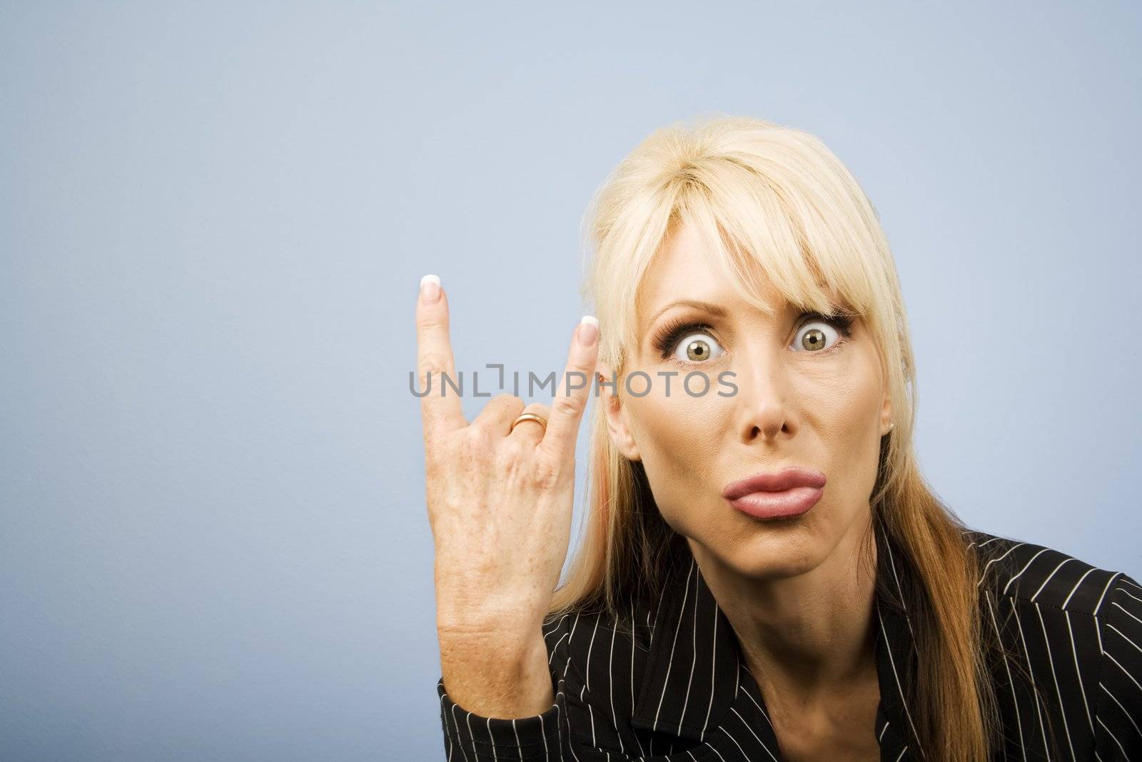 Businesswoman in a pinstripe suit making a bull horns sign