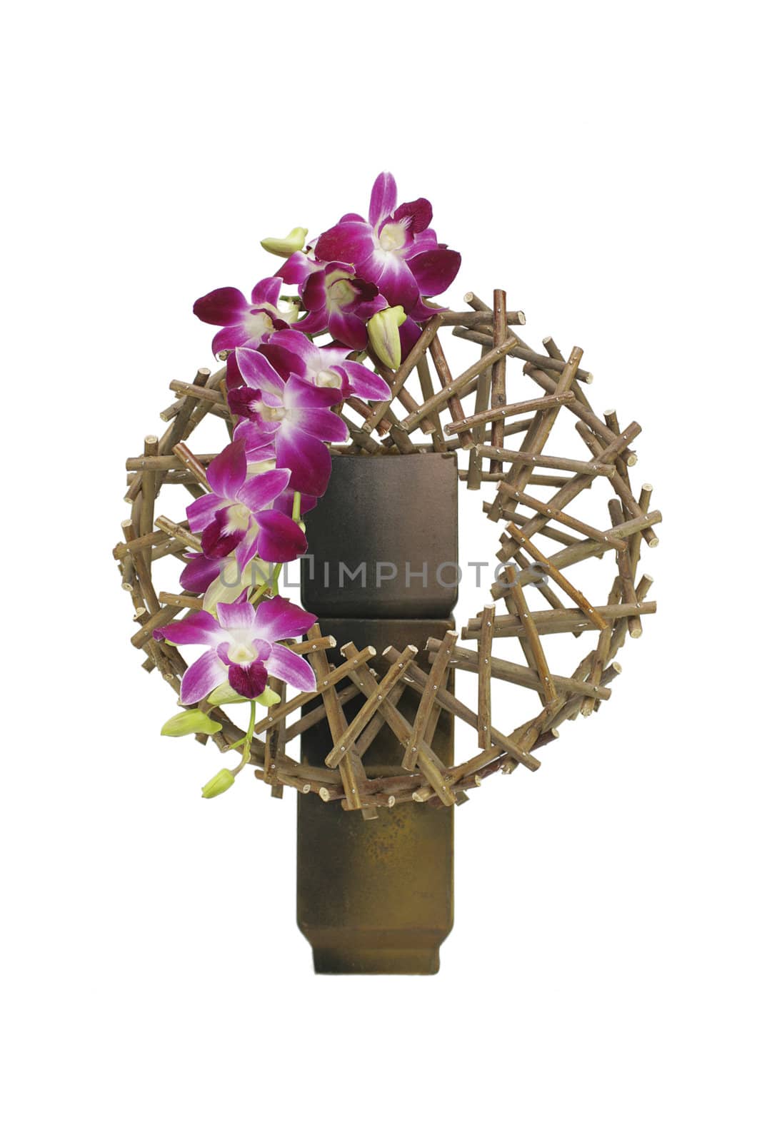 An oriental styled flower arrangement set on an isolated white background. Pink flowers cascading from a circular wooden structure set in a rustic ceramic vase.
