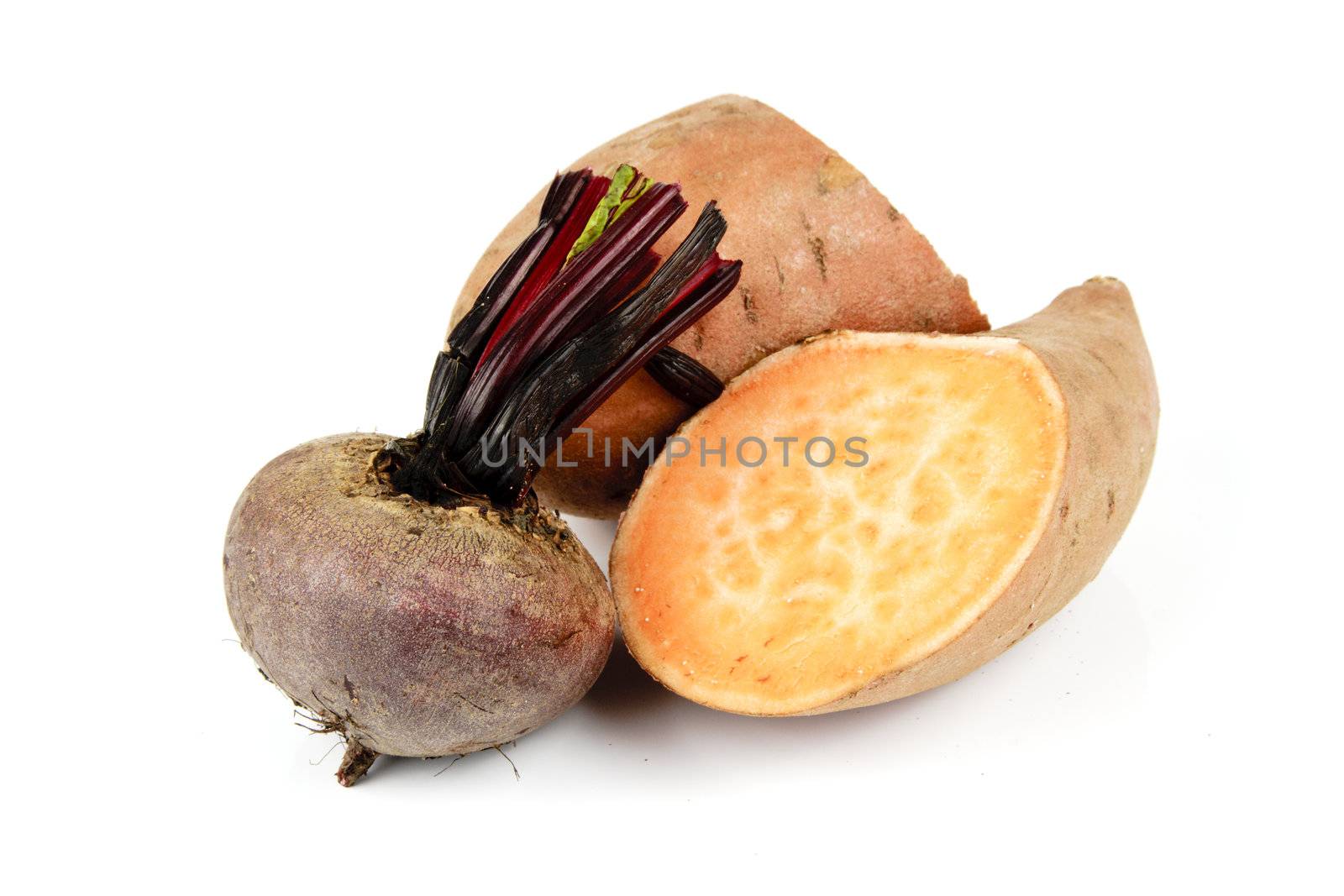 Sweet Potato cut in half with a small uncooked beetroot on a reflective white background
