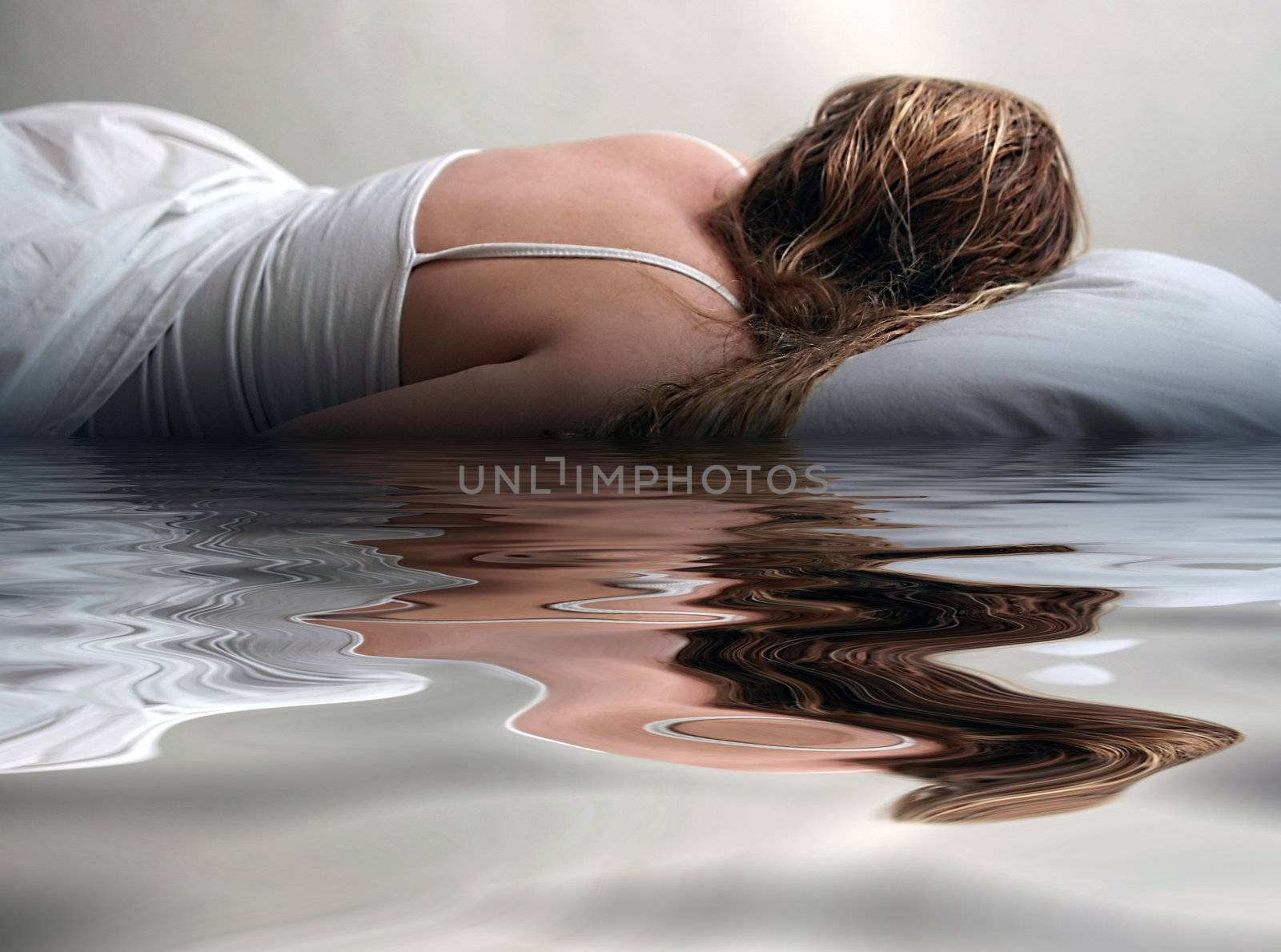 Woman lying in bed reflected in water