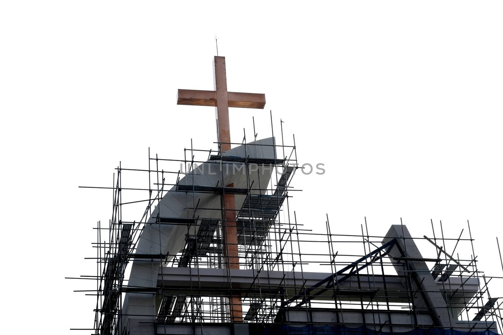 Golden cross with scaffolding against a white sky
