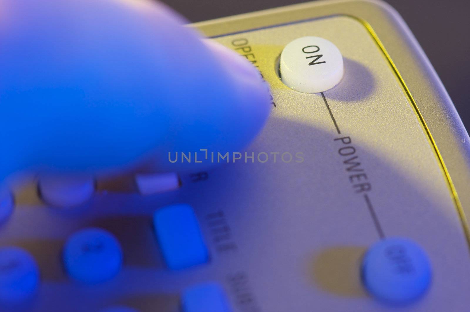 Abstract Remote with Finger Heading for the On button.