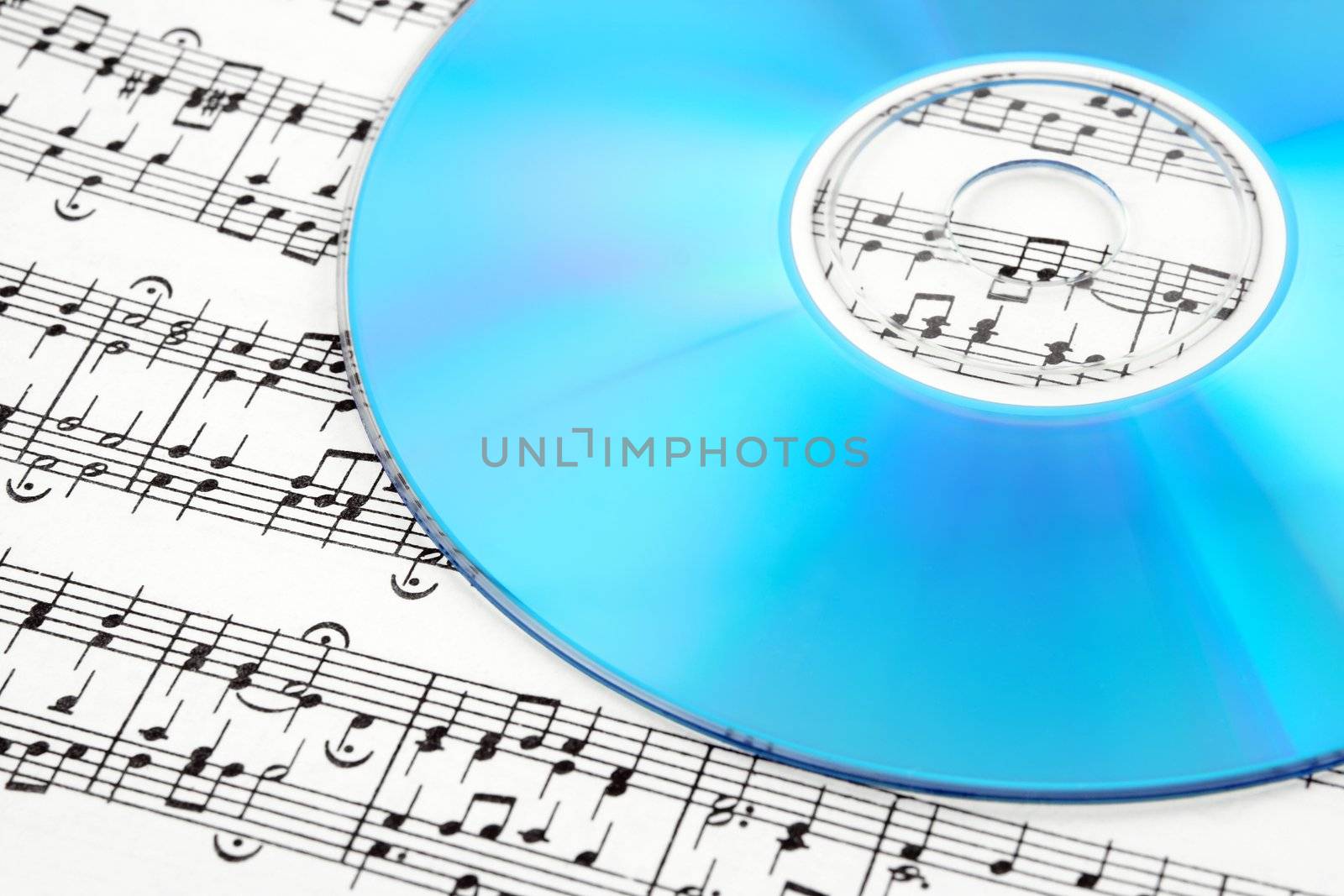 Blue CD or DVD on sheet music. Digital music concept.