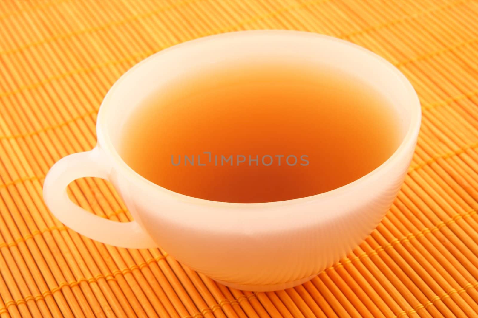 Cup of tea on a rattan mat in warm golden light.