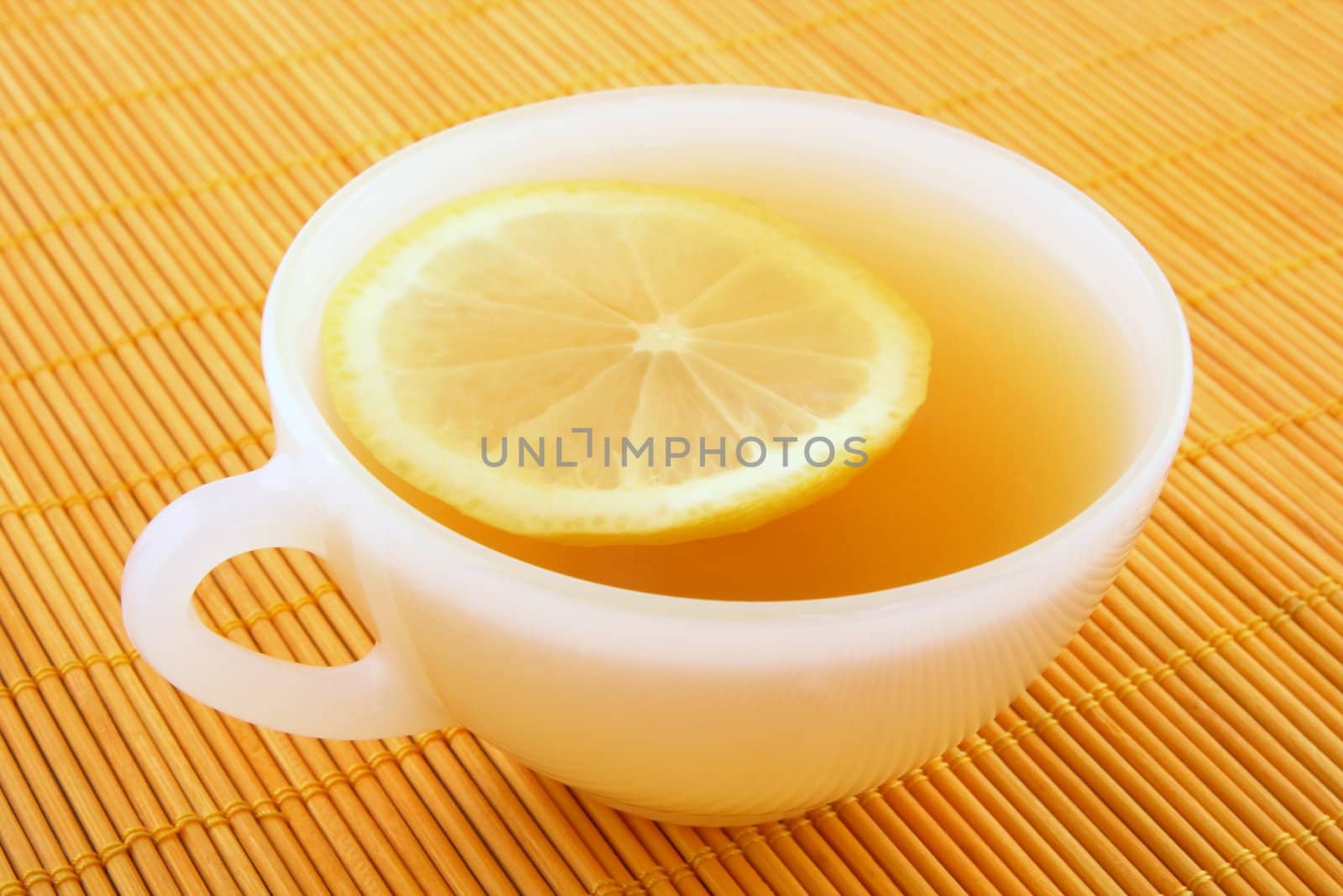 Cup of tea with lemon in warm golden light by anikasalsera
