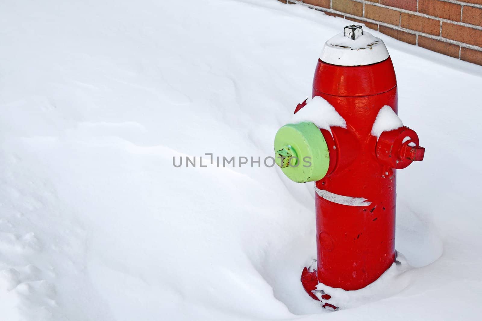 Red fire hydrant on the sidewalk covered by snow.