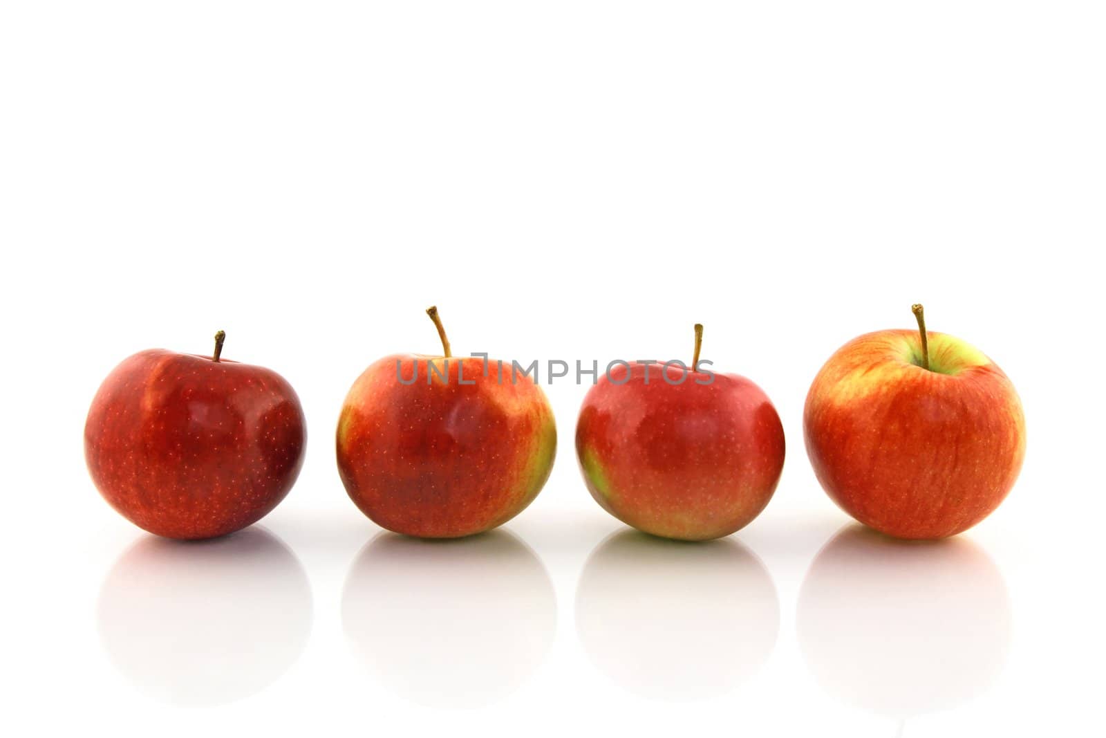 Four red apples in a row, reflecting on white background.