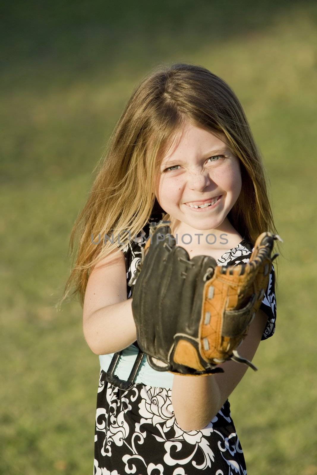 Cute young girl in summer dress with a baseball