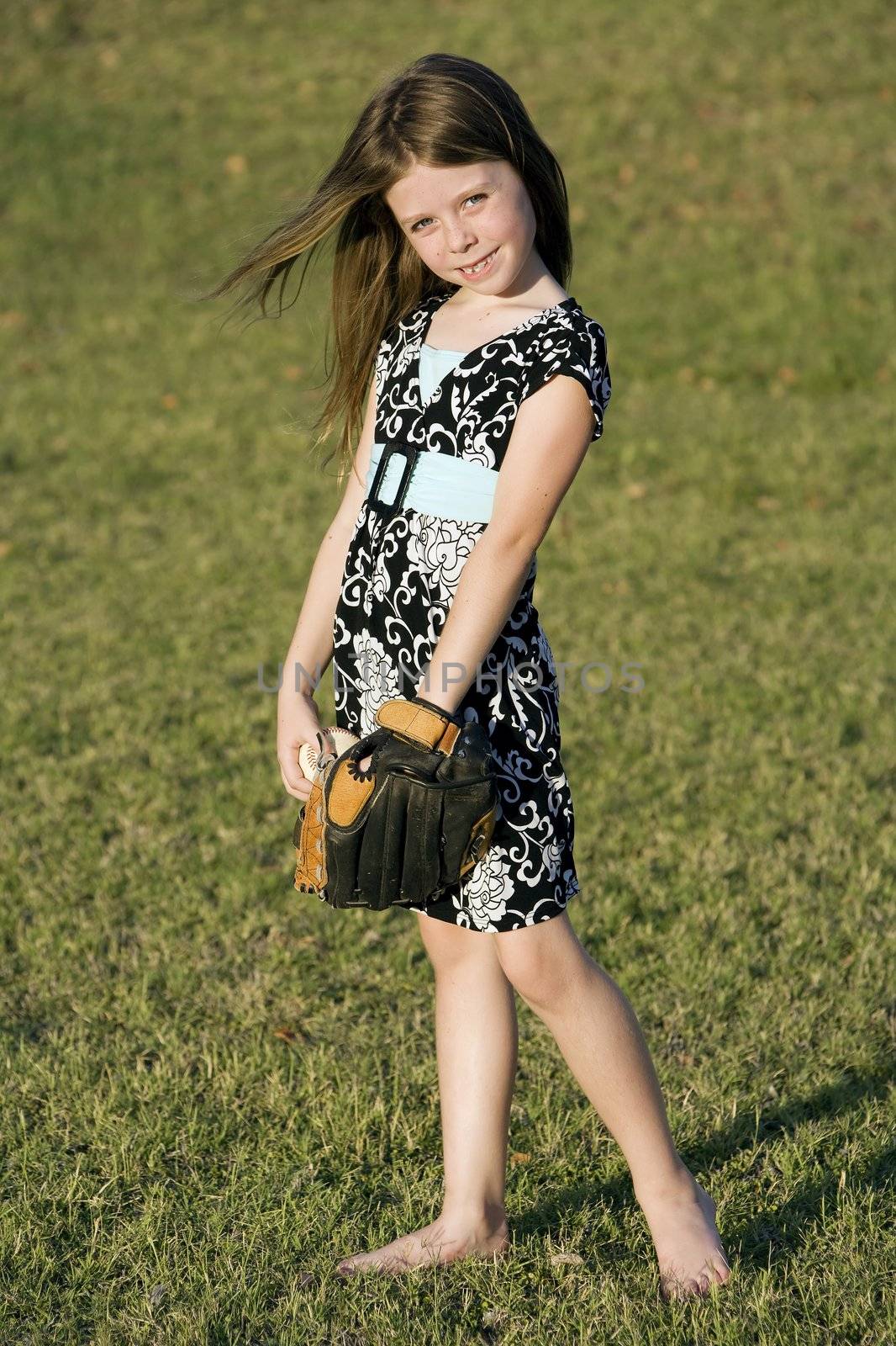 Cute young girl in summer dress with a baseball