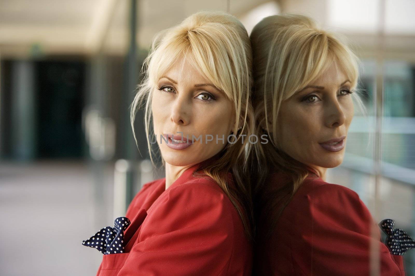 Blonde Businesswoman leaning against a reflective surface