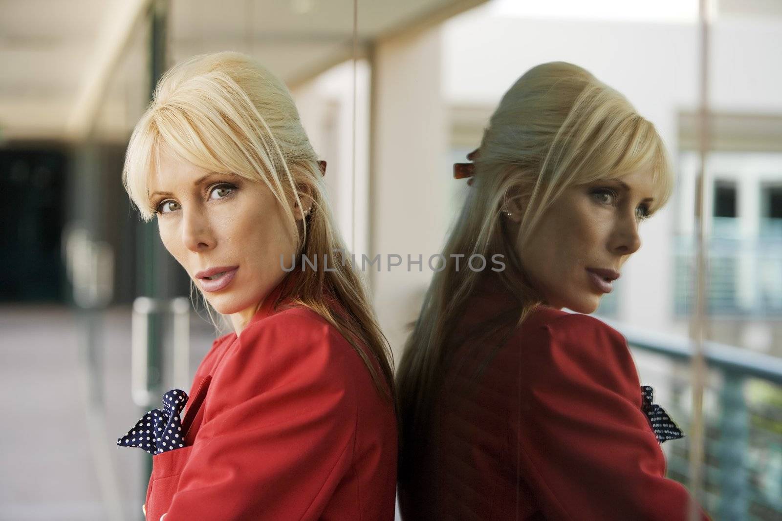 Blonde Businesswoman leaning against a reflective surface