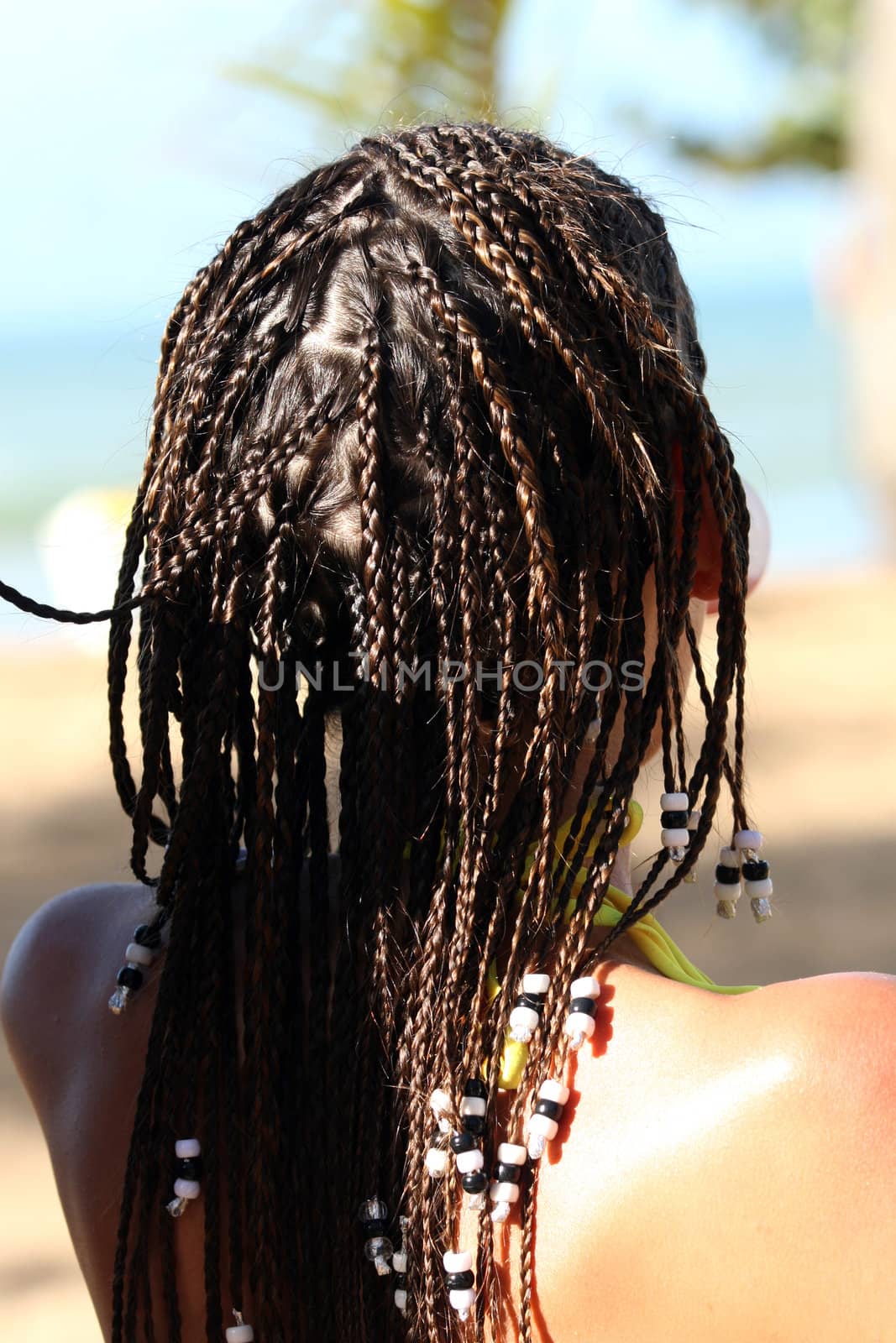 Close-up of the braids from behind, woman sitting on the beach