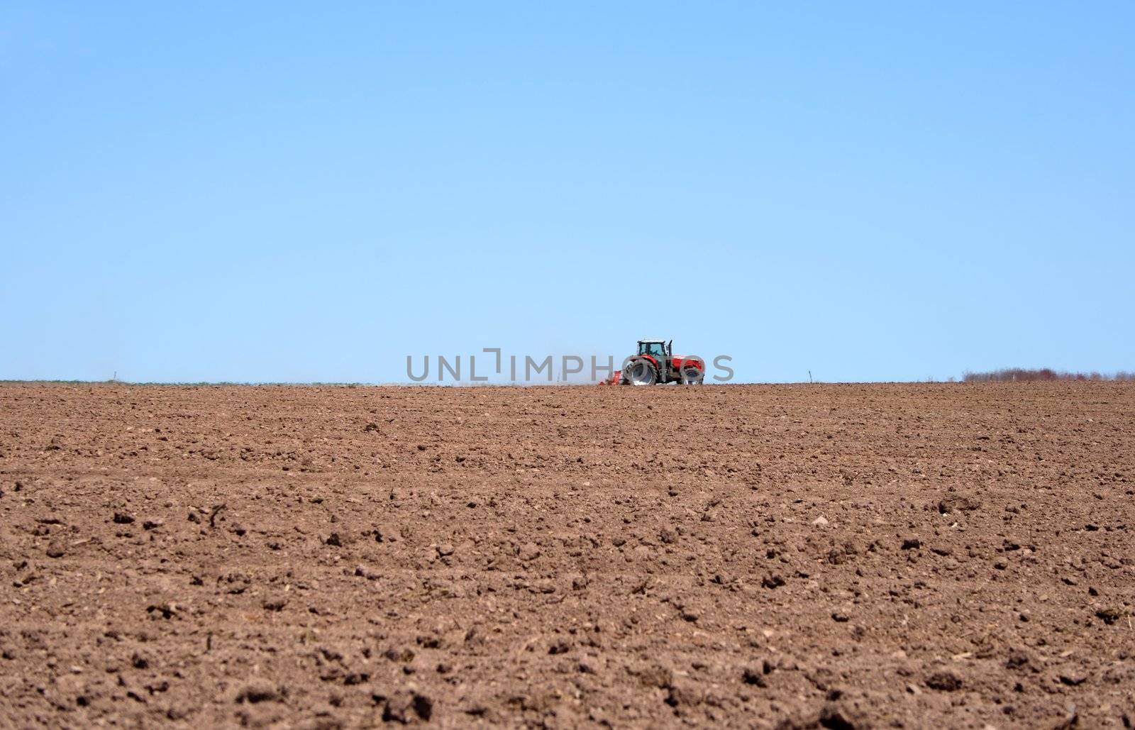 Farmer working on him tractor in the spring field, plowing land.