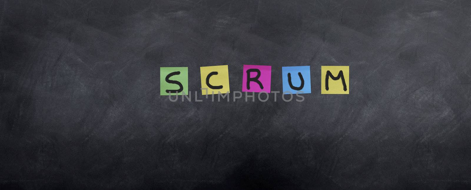 The Agile project methodology 'Scrum' is spellt on a blackboard with post it notes.