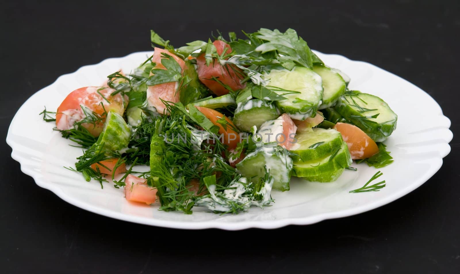 salad on a white plate on a black background