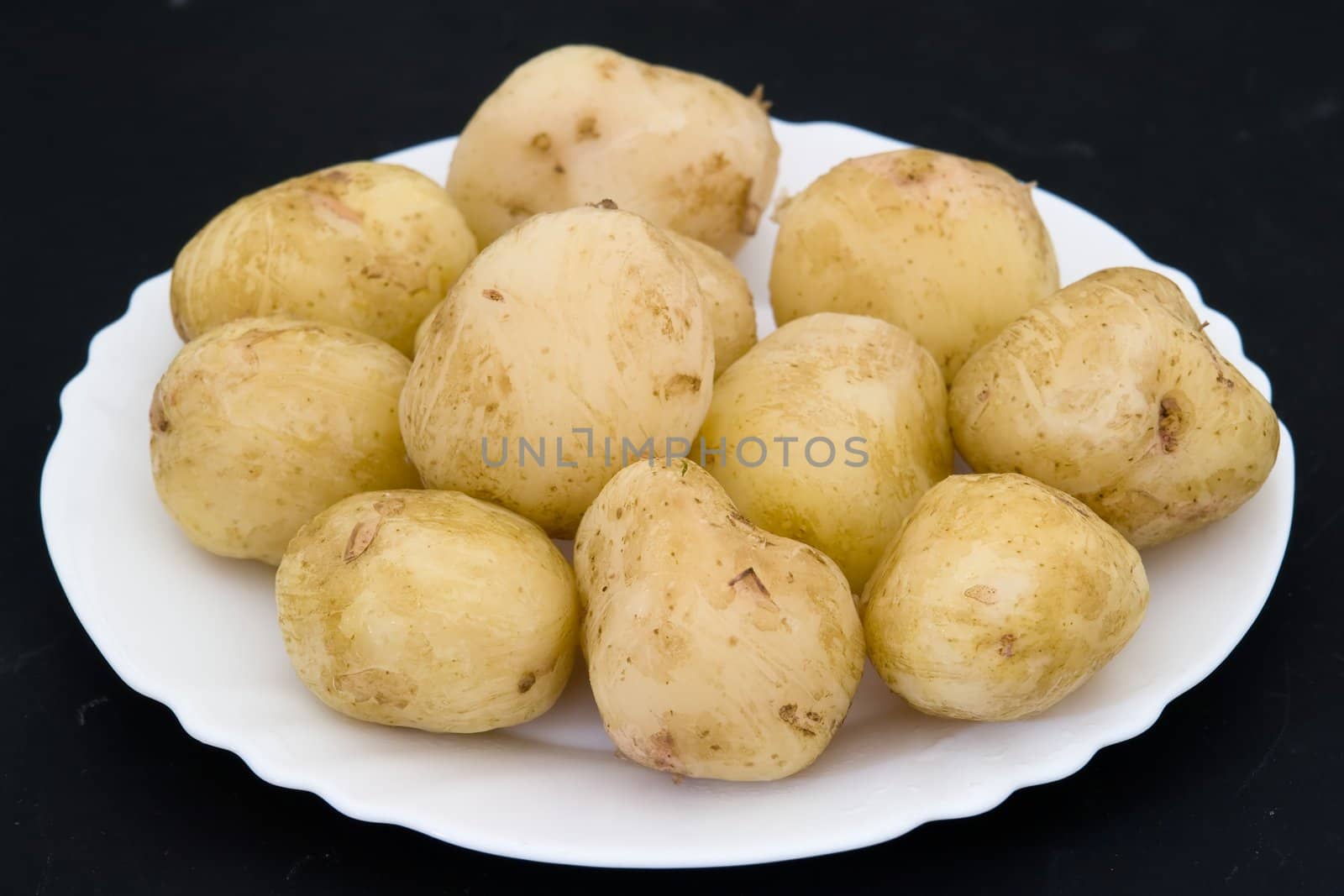 Potatoes on a white plate on a black background
