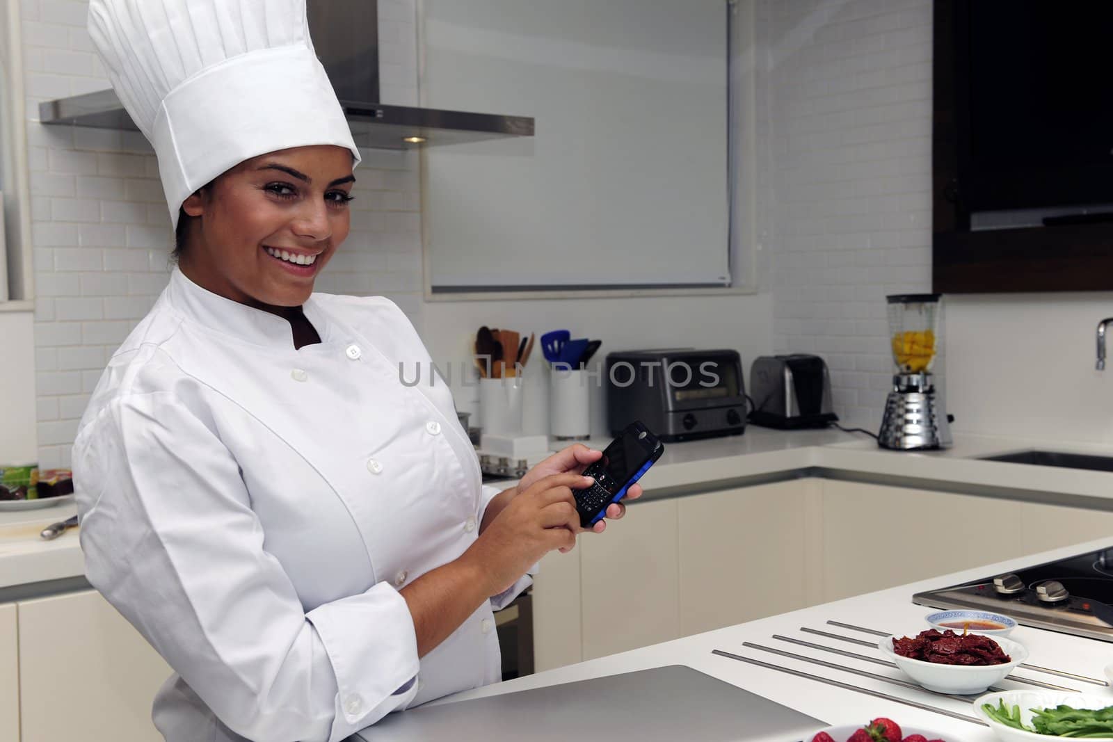 Happy chef cooking in kitchen and typing sms