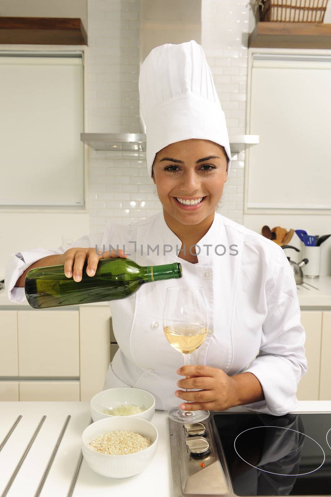 Happy chef cooking using white wine in kitchen