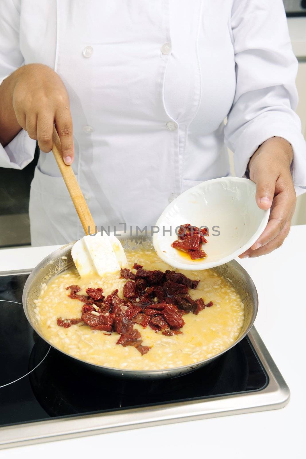 Chef cooking risotto adding dried tomato