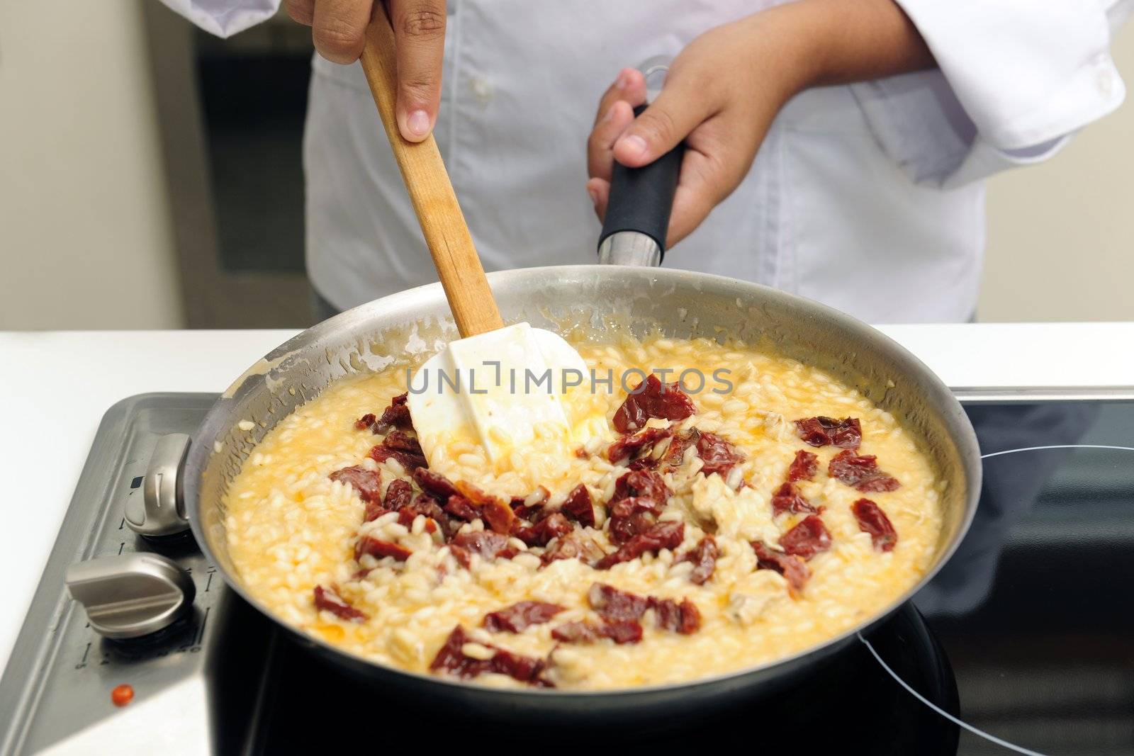 Chef cooking risotto with dried tomato stirring