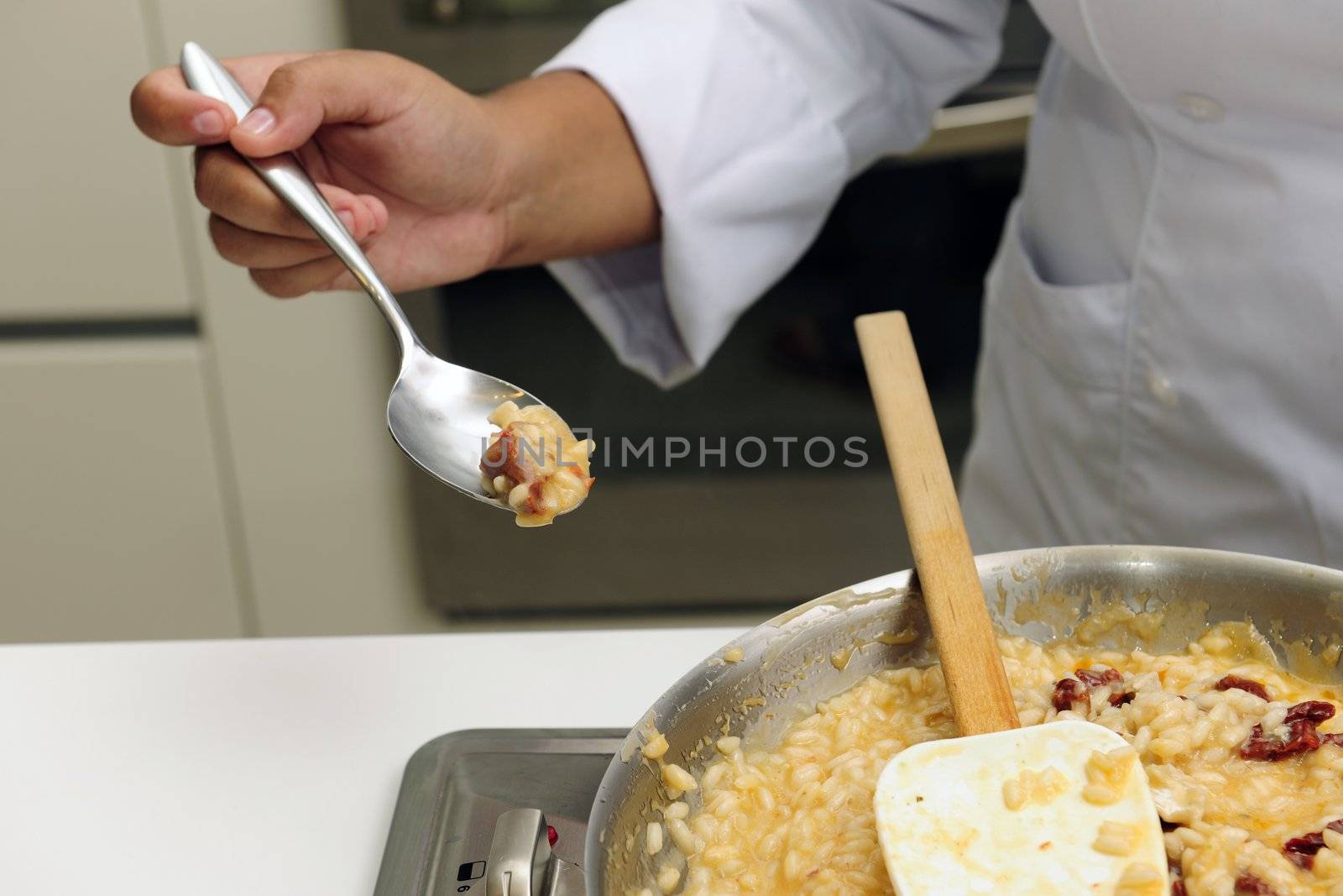 Chef cooking risotto with dried tomato stirring