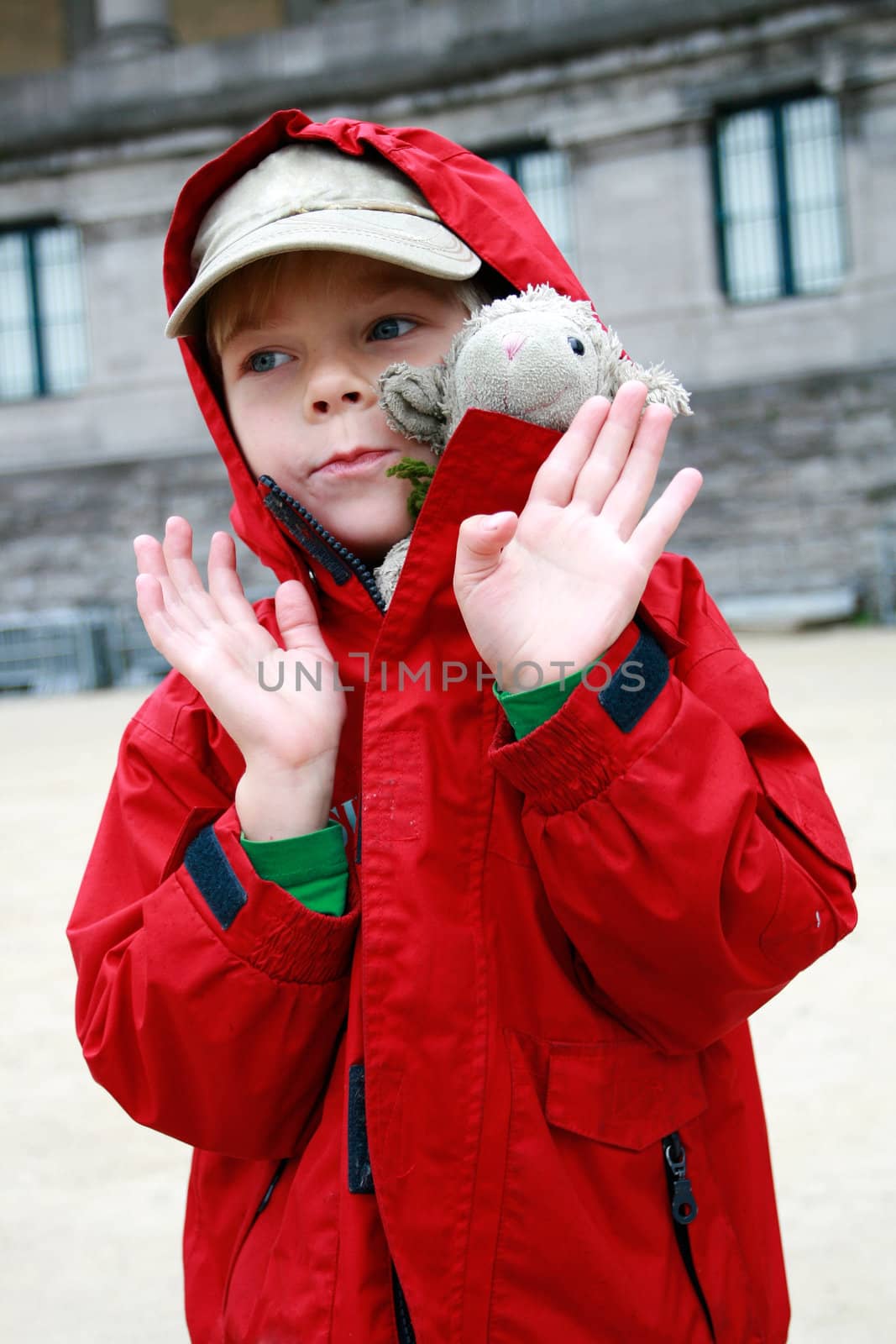 Portrait of smal boy in red jacket with toy lambkin