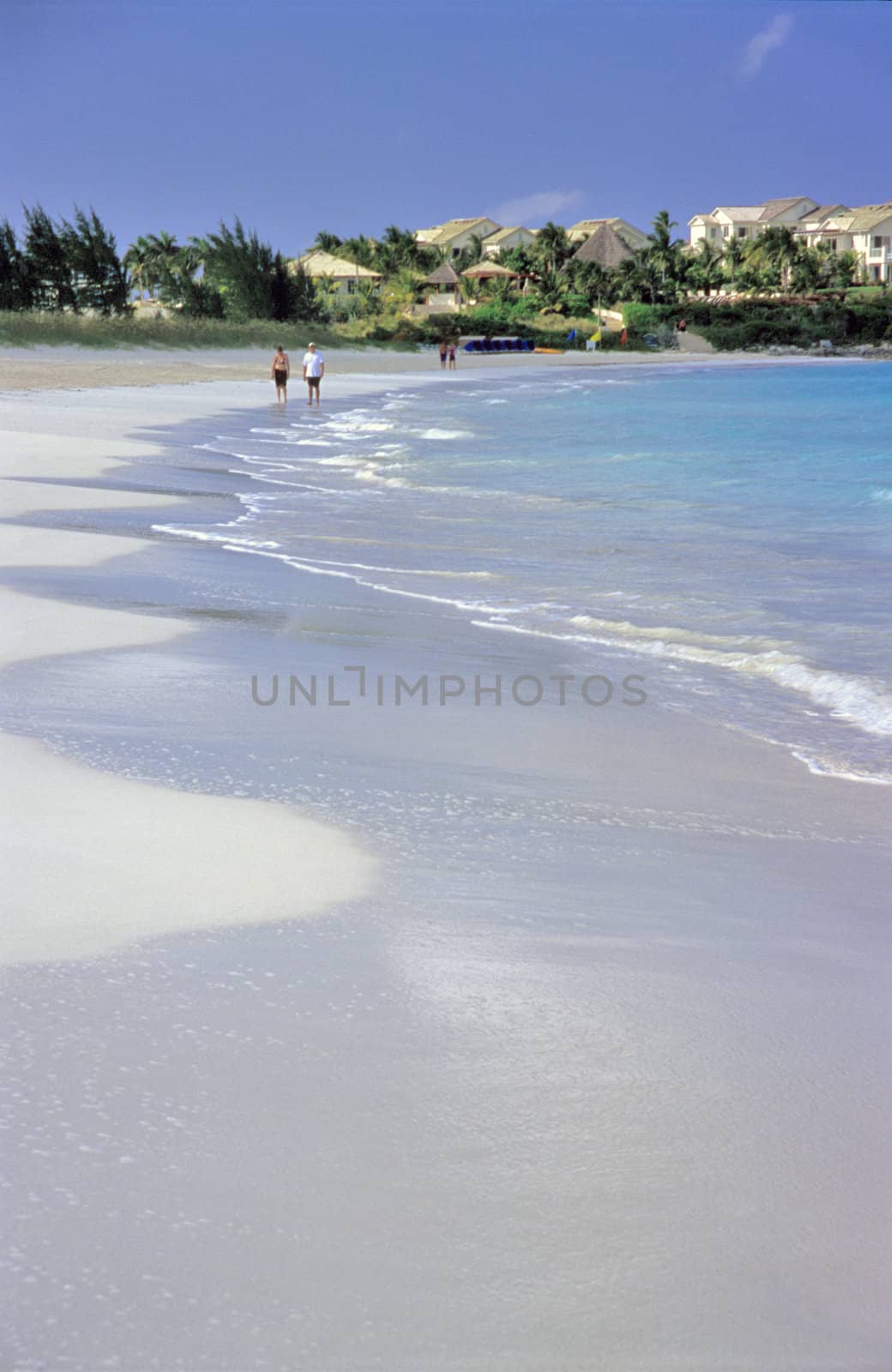 A couple walks on a white sandy beach on the Romantic Great Exuma Island, The Bahamas.