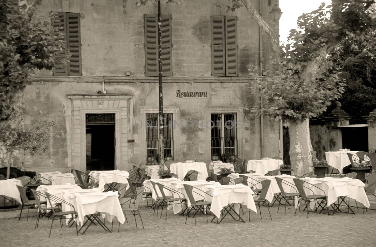 A quaint restaurant exterior with tables set and waiting for diners in the South of France. Sepia Toned.