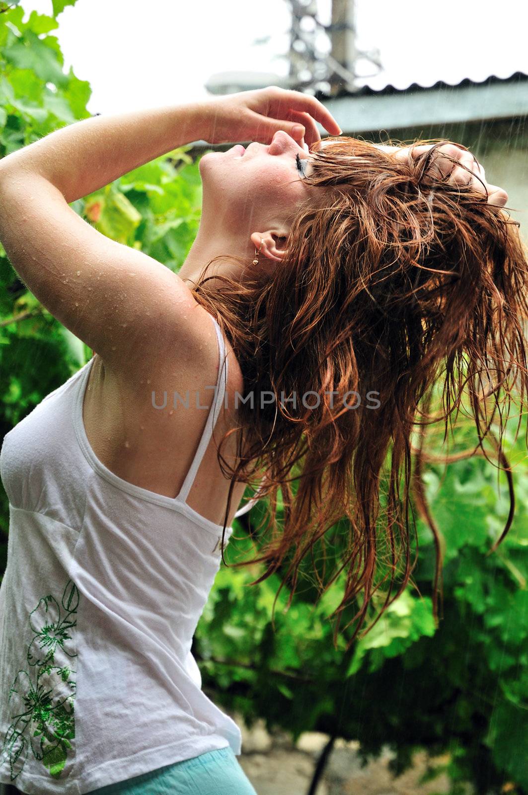 redheaded beautiful girl is standing under the rain, she enjoying it