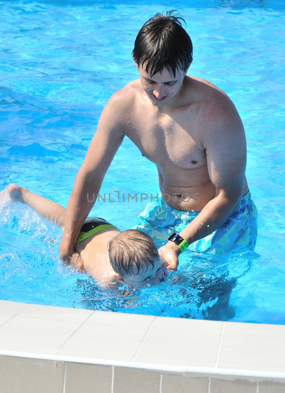 father teaching his little son to swim, boy is already under the water