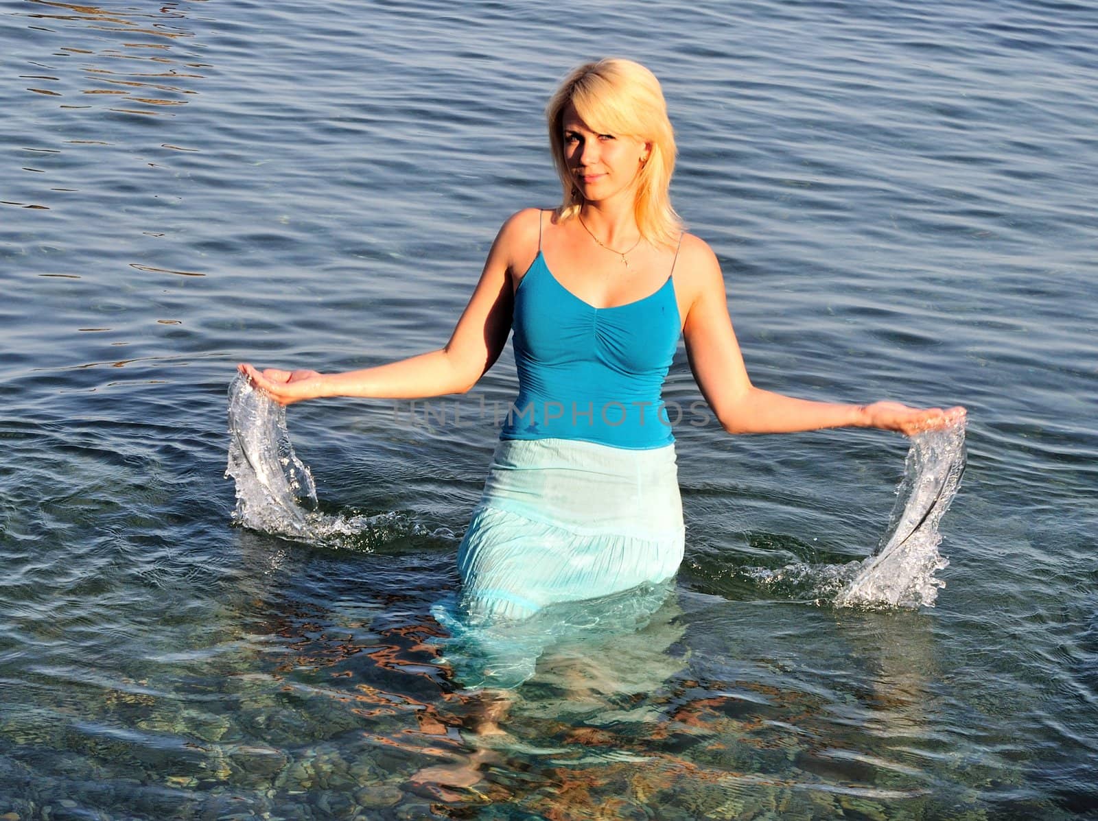 beautiful girl is standing in the sea,  her hand are full of water