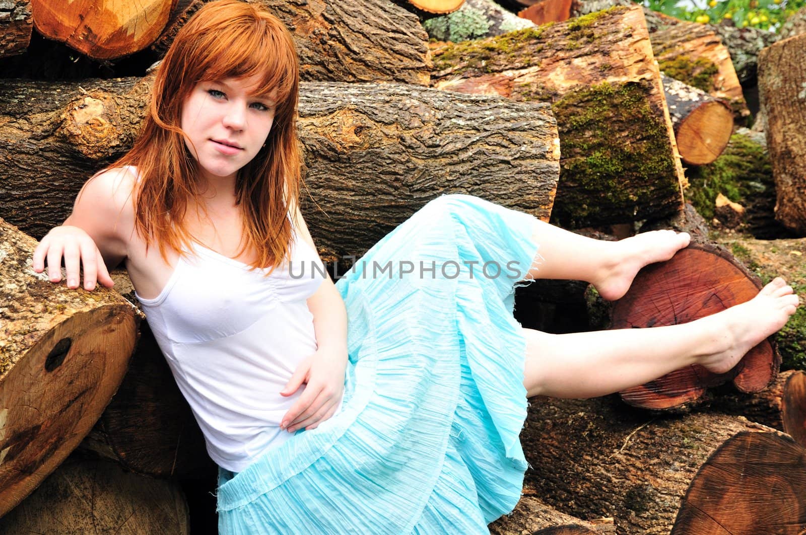 beautiful redheaded girl having sunbath on 	 cord wood
