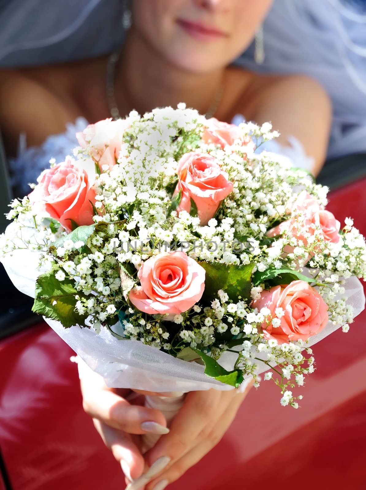 bride is sitting in the car and holding wedding pink flowers