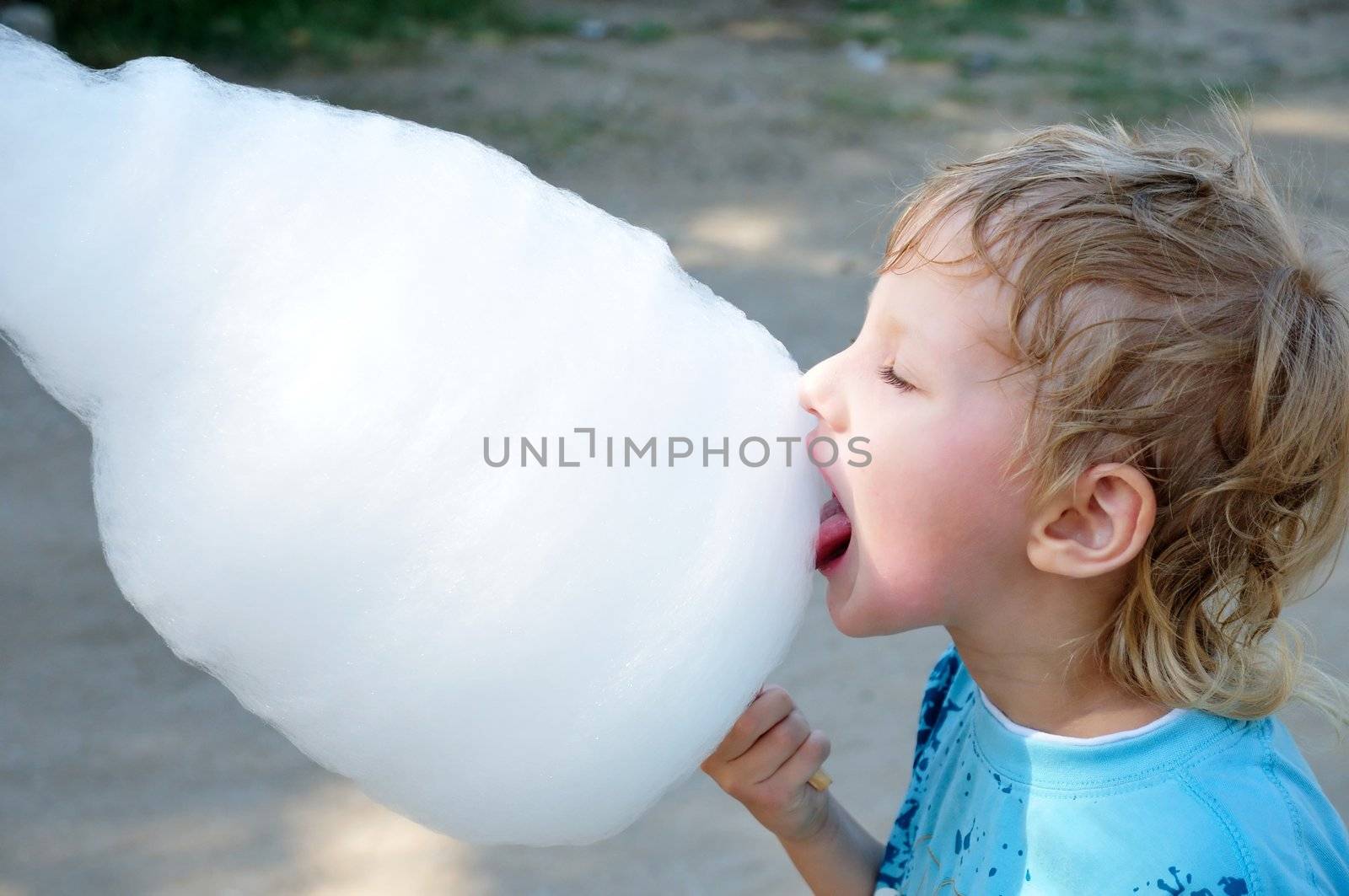 little boy is enjoying cotton candy  in hot summer day