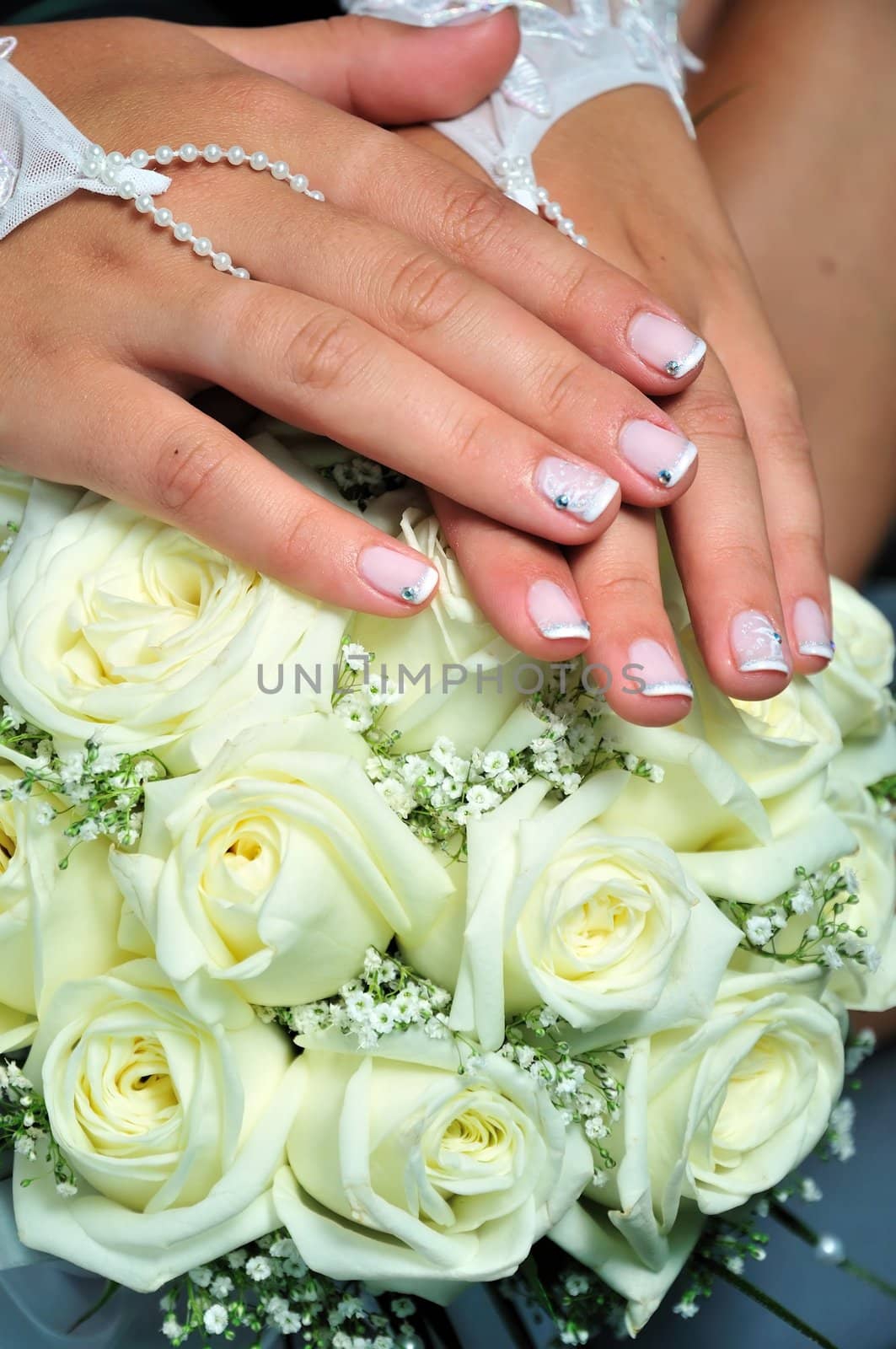 wedding manicure on hands of bride, they are laying on weddind flowers 